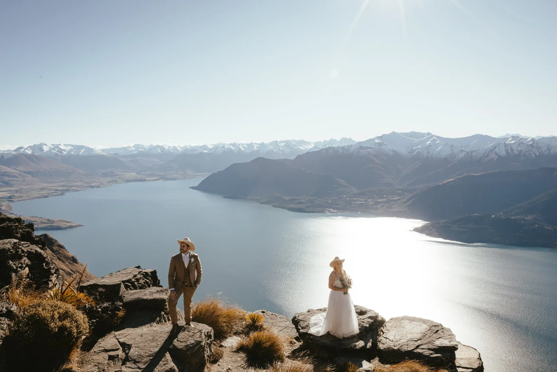 Wide spring view from the Cecil Peak Ledge, a couple facing each other above Lake Wakatipu.