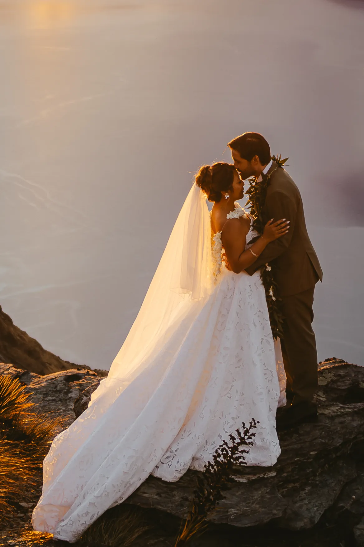 Close portrait of a couple kissing, her veil catching the sunset light, on Cecil Peak in Queenstown.