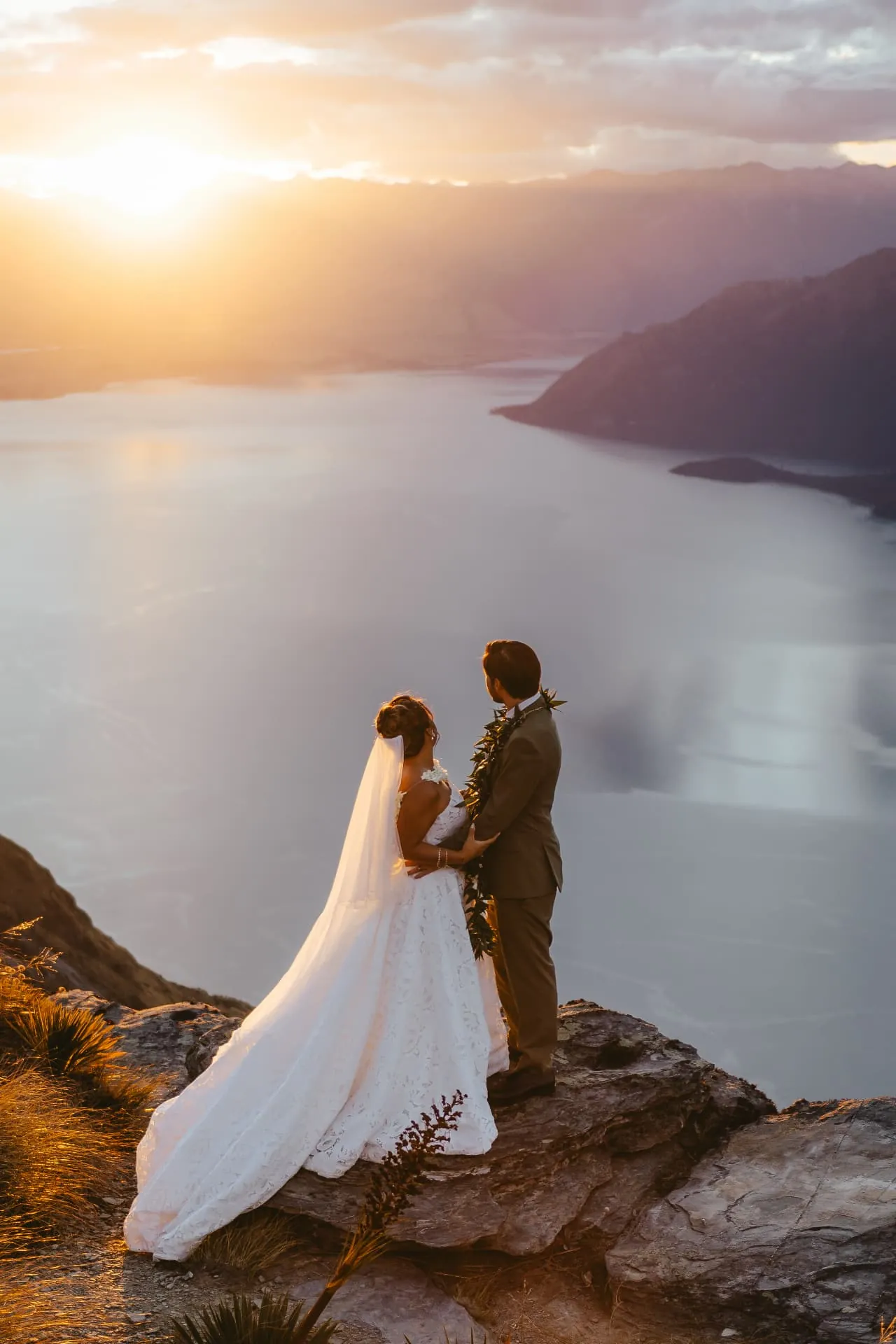 Wedding couple standing together at sunset on Cecil Peak, a Queenstown heli wedding above Lake Wakatipu.