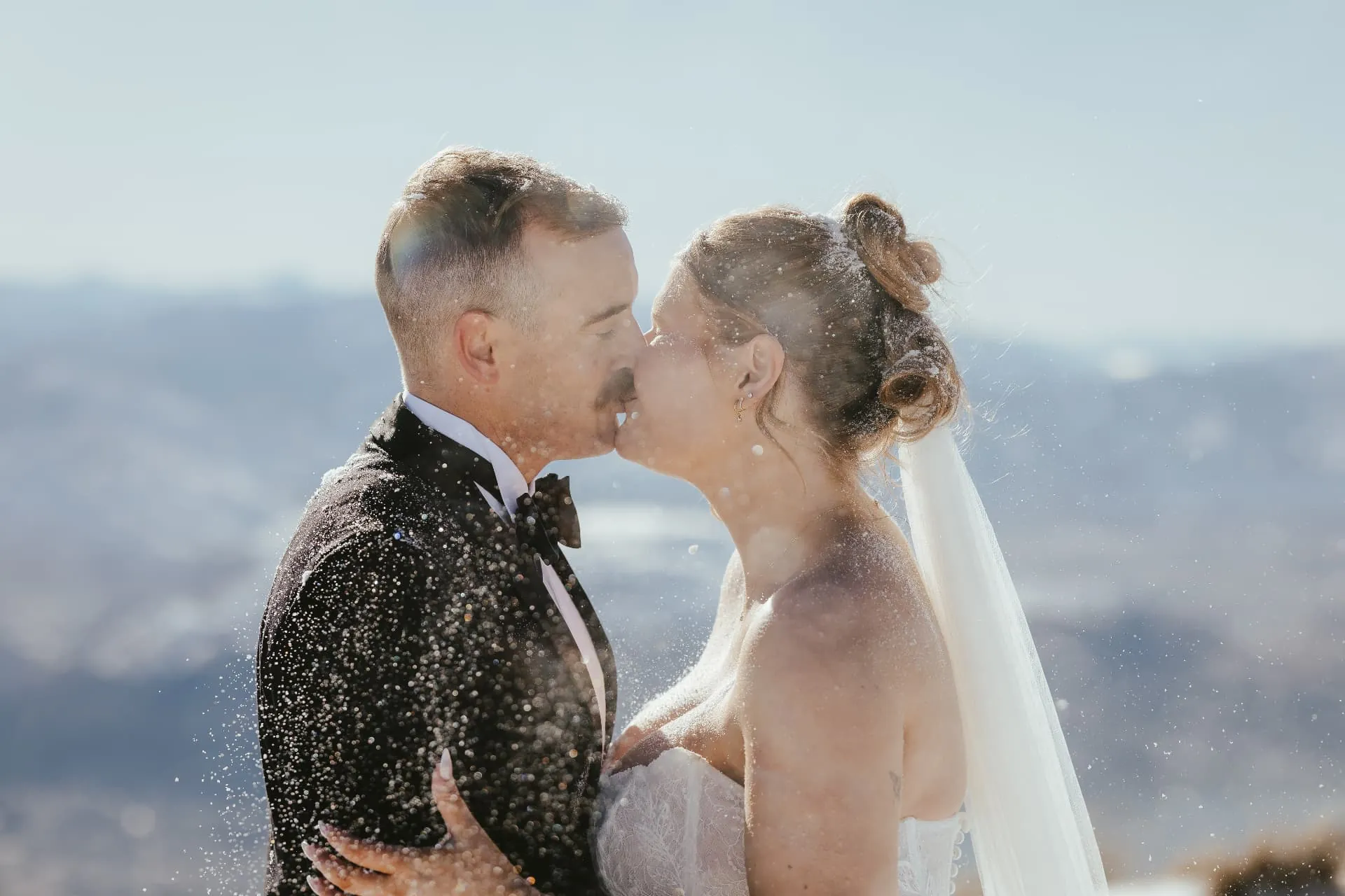 Couple kissing in a flurry of snow on the Spur at Cecil Peak, Queenstown.