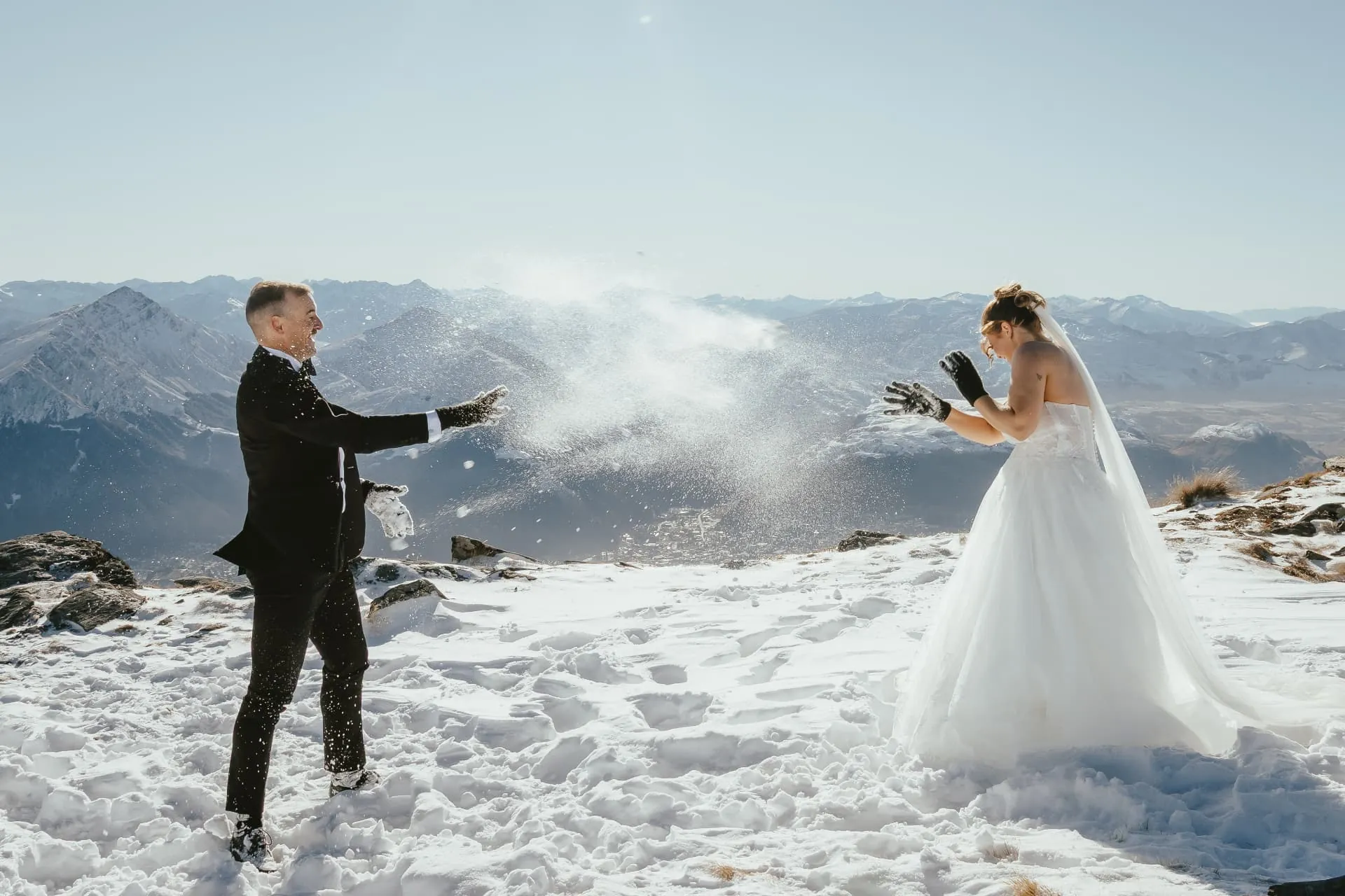 Bride throwing snow at the groom during their winter elopement on Cecil Peak, Queenstown.