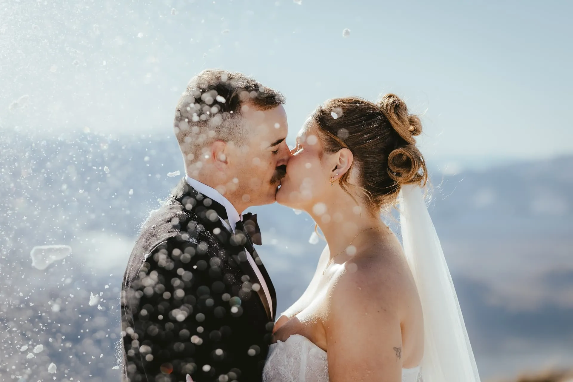 Couple kissing with snow falling around them after a snowball fight on Cecil Peak.