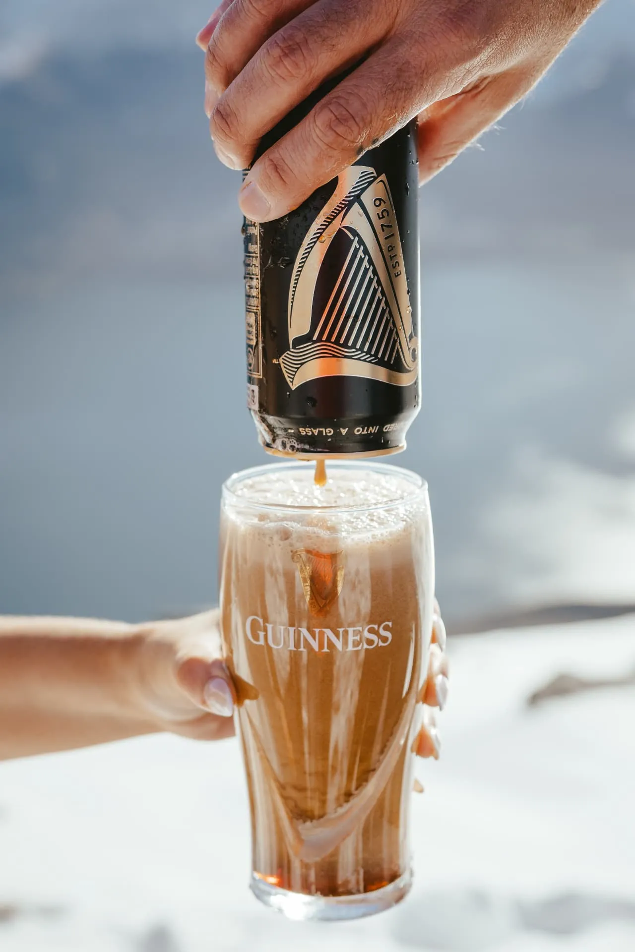 Pouring a celebratory drink in the snow on Cecil Peak during a winter elopement.