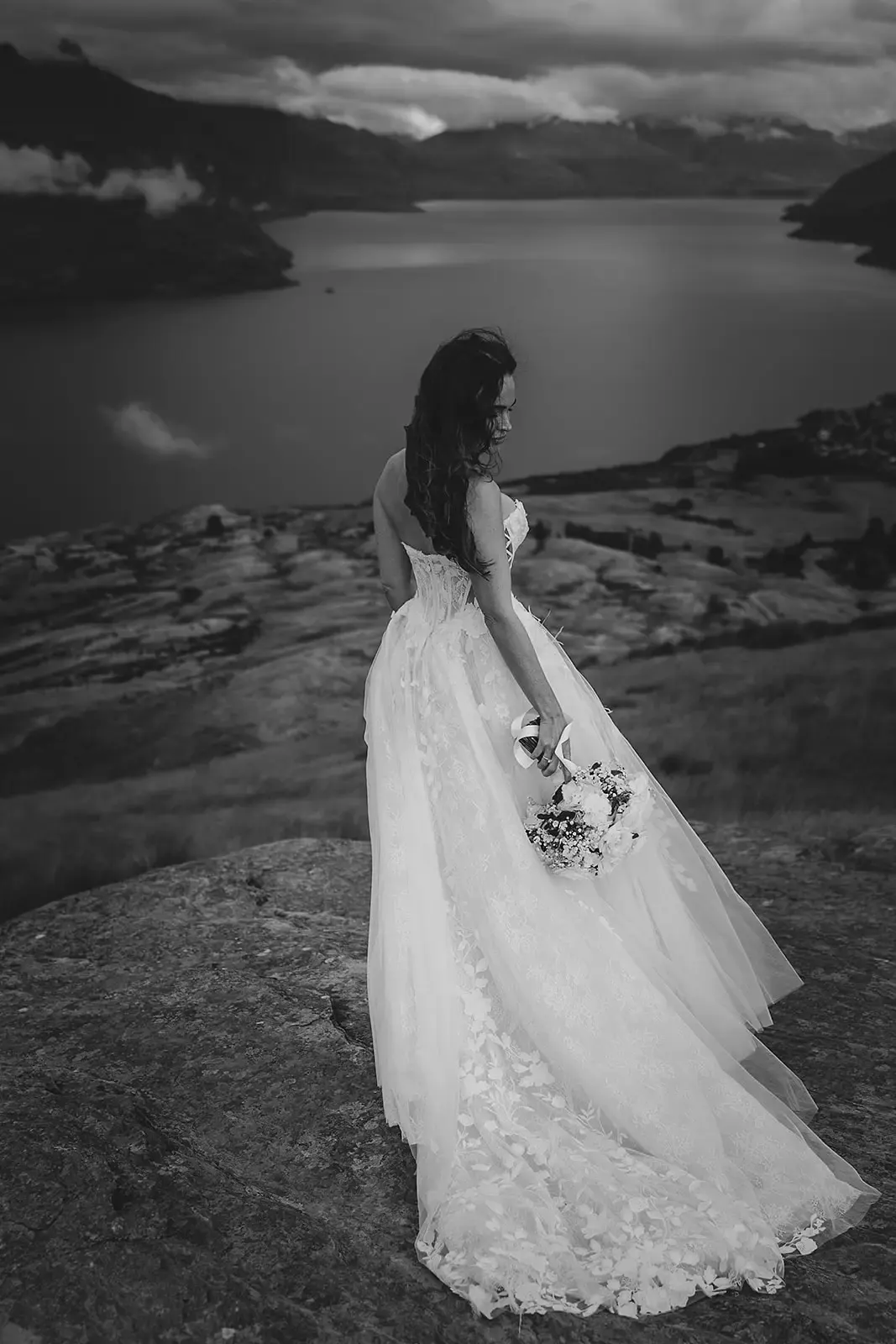 Black and white portrait of a bride on the ledge above Lake Whakatipu