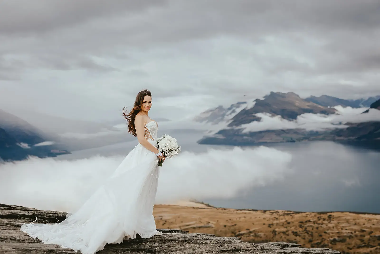 Bride with bouquet on the western ledge above a cloud inversion at Deer Park Heights