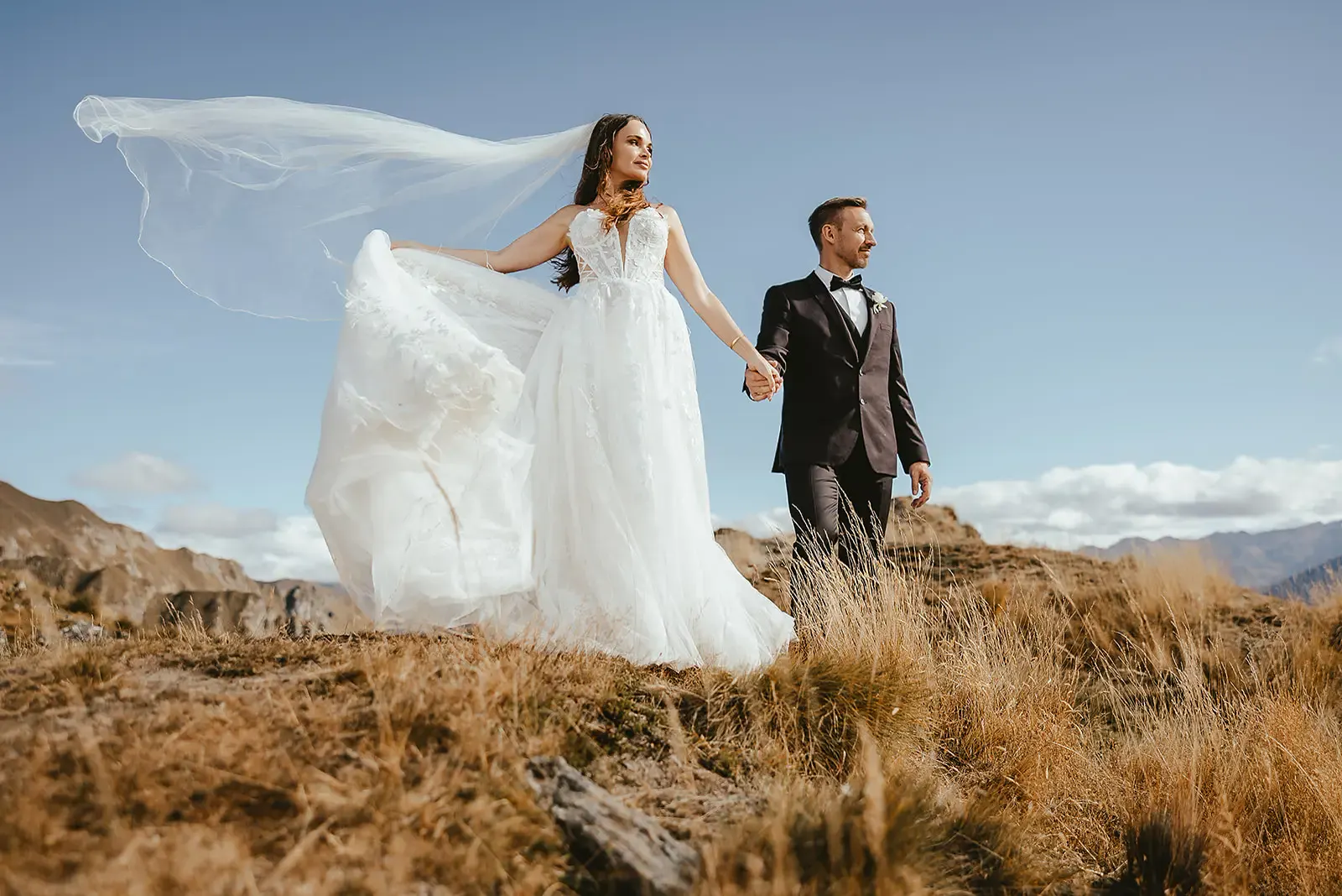 Bride's veil lifting in the wind as she walks hand in hand with the groom at Deer Park Heights