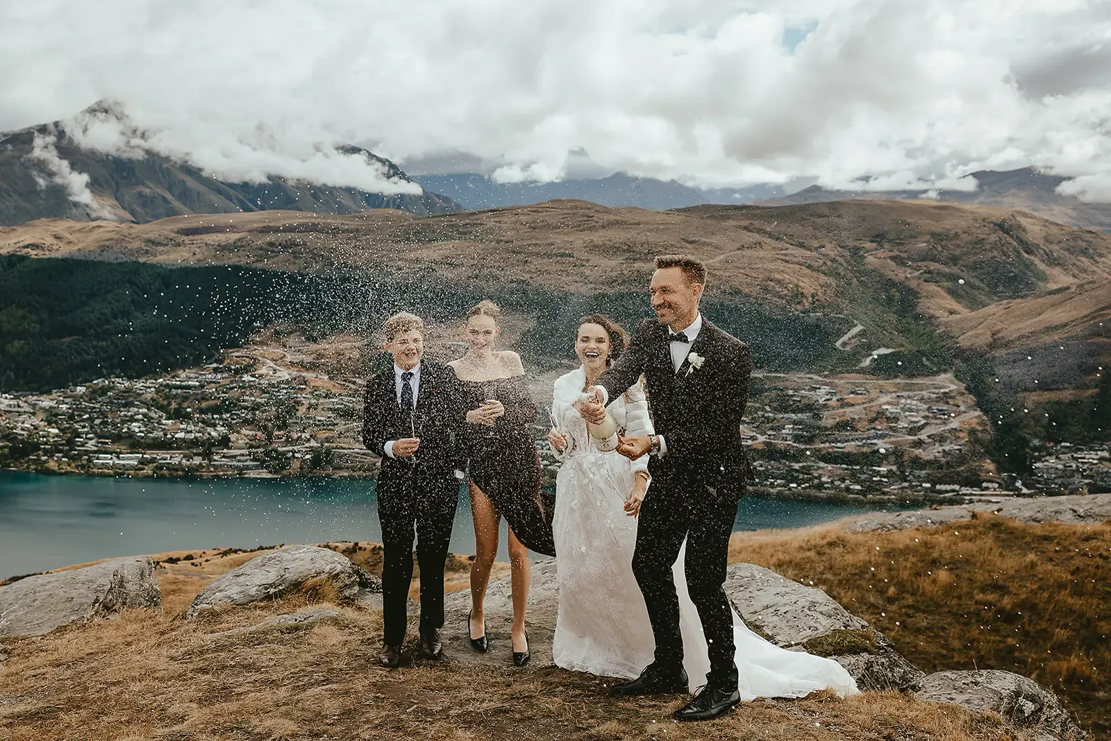 Family spraying champagne after a Deer Park Heights ceremony, Lake Whakatipu behind