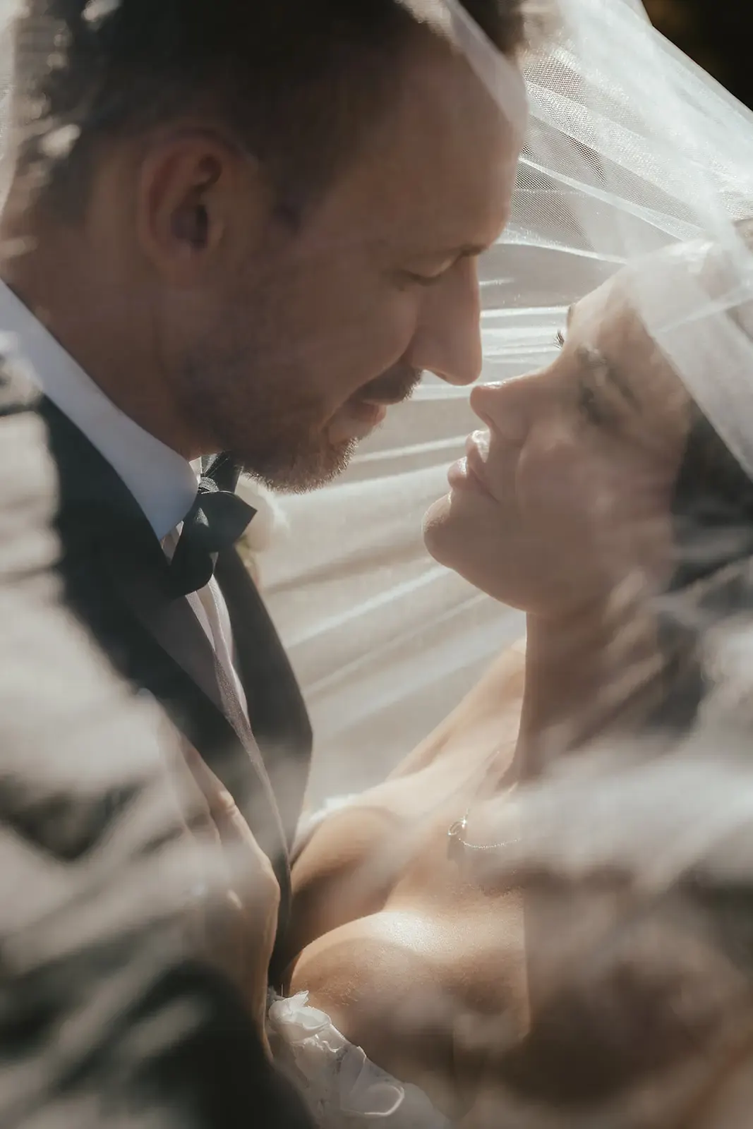 Bride and groom face to face under her veil in golden light at Deer Park Heights