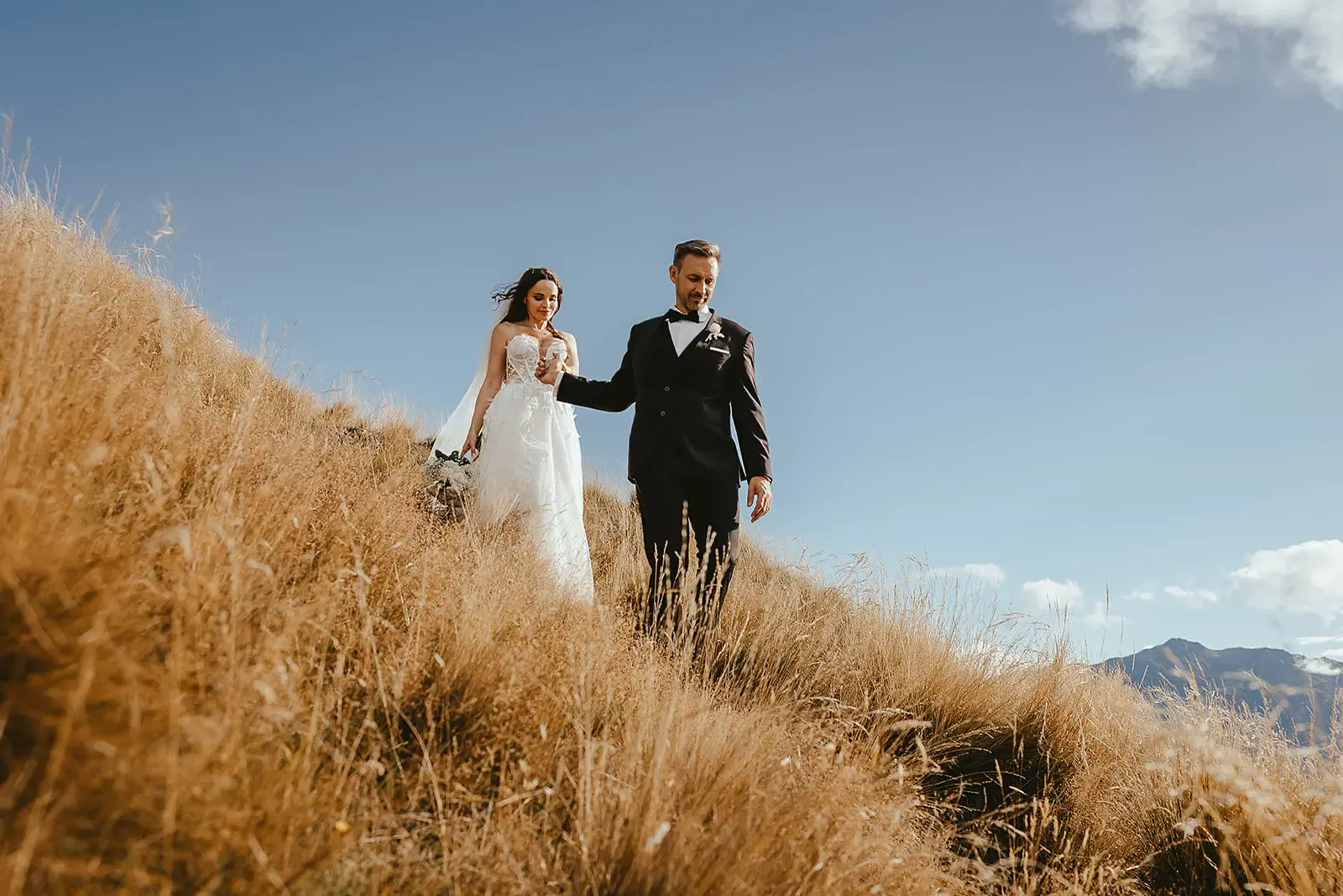 Couple walking up a golden tussock slope at Deer Park Heights