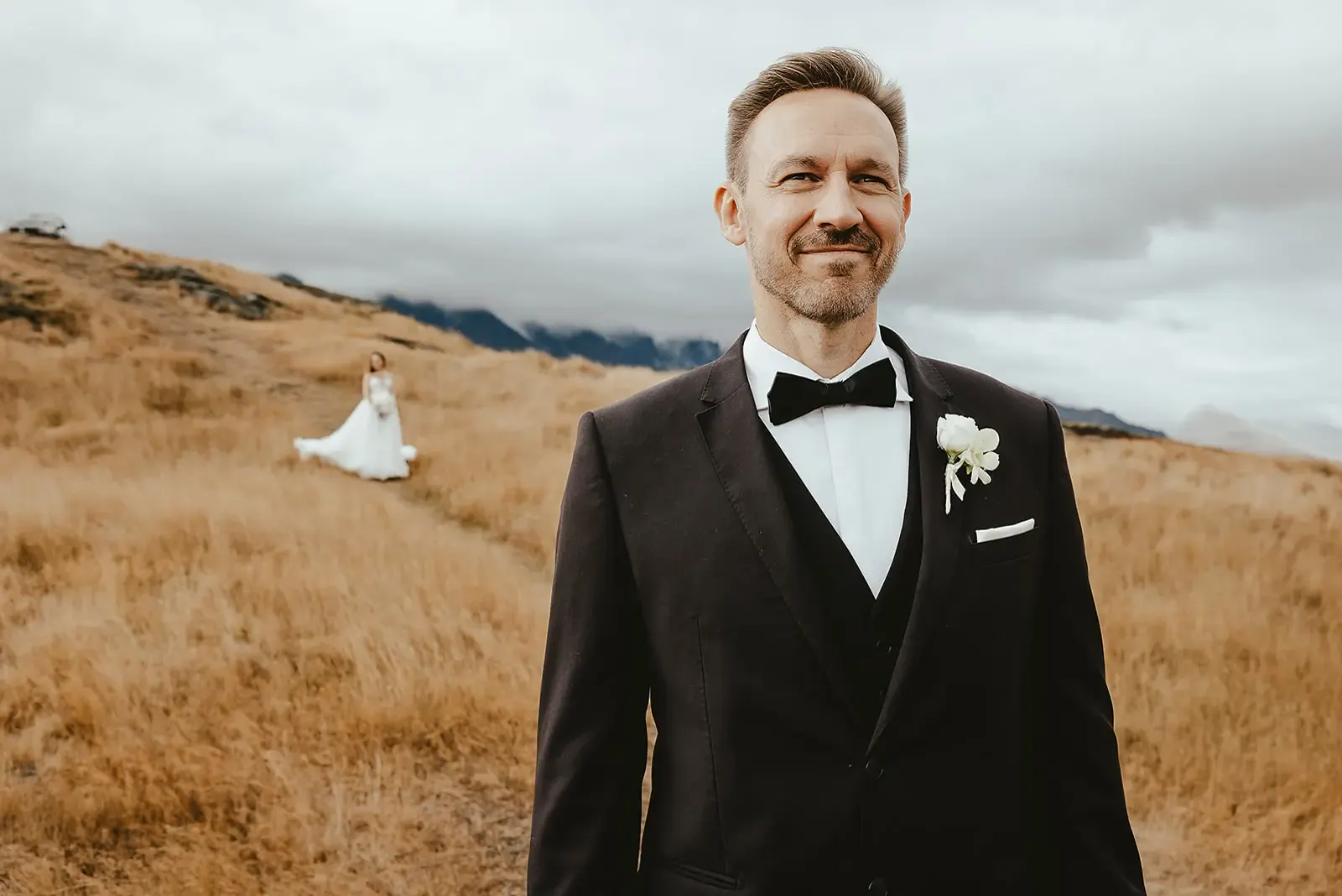 Groom waiting with his back turned on a tussock path before the first look at Deer Park Heights
