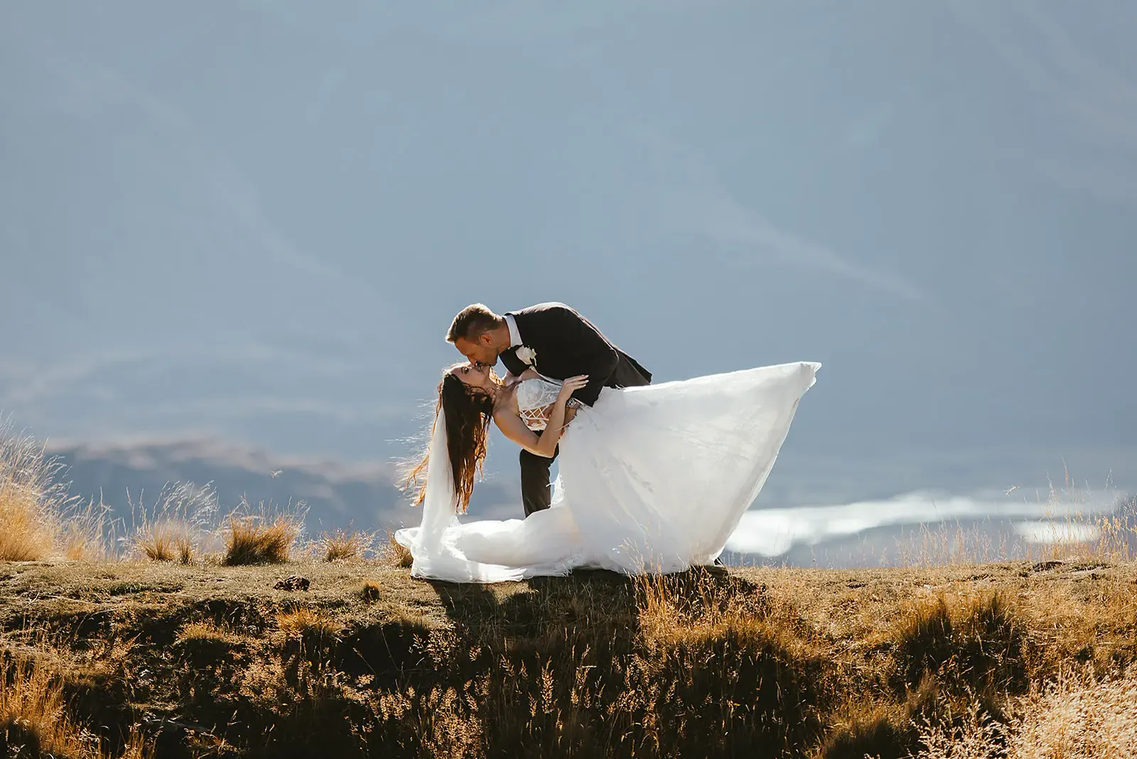 Groom dipping the bride for a kiss on the tussock ridge at Deer Park Heights