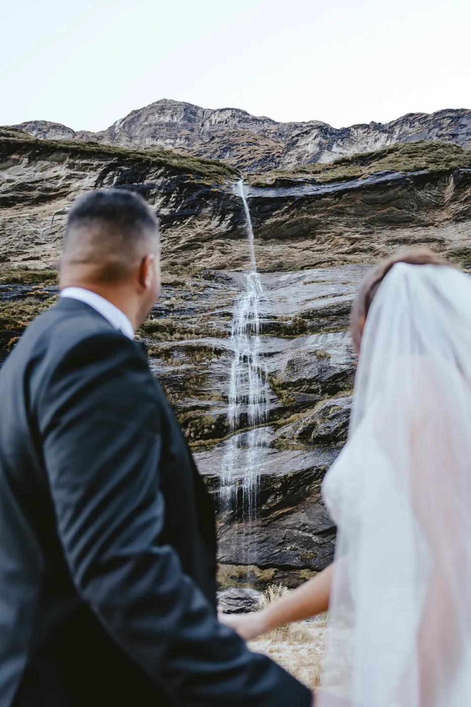 Groom and bride looking up at the main Earnslaw Burn waterfall, the only one still flowing in early winter