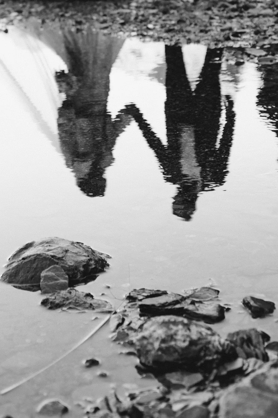 Black and white reflection of a bride and groom holding hands in a still pool at Earnslaw Burn