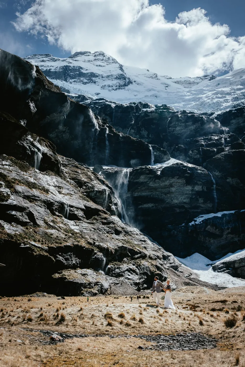 Eloping couple small in the Earnslaw Burn basin beneath Mount Earnslaw, Mount Aspiring National Park.