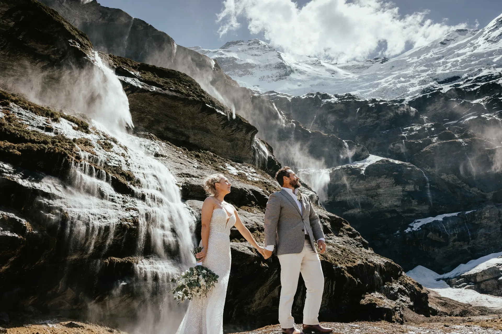 Heli elopement couple beneath the glacier-fed waterfalls of Earnslaw Burn, New Zealand.