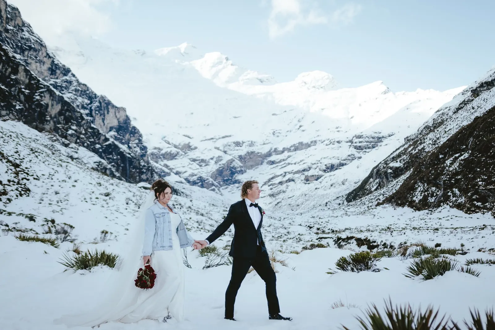 Bride and groom walking hand in hand through deep snow in the Earnslaw Burn glacier valley