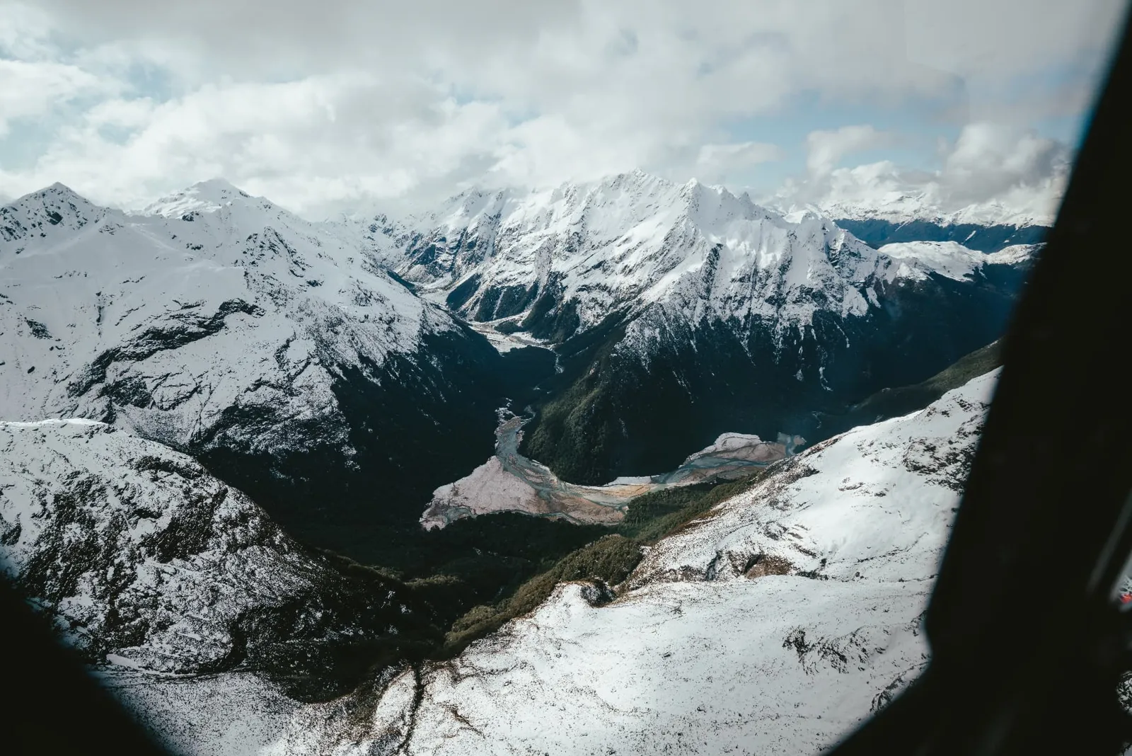 Winter helicopter flight over snow-covered mountains and valleys on the way to Earnslaw Burn near Glenorchy