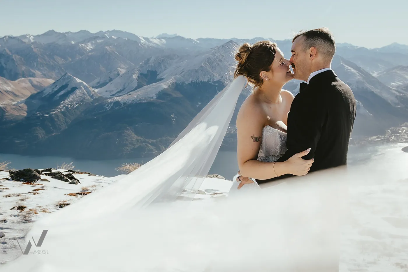Bride and groom kissing beneath a veil