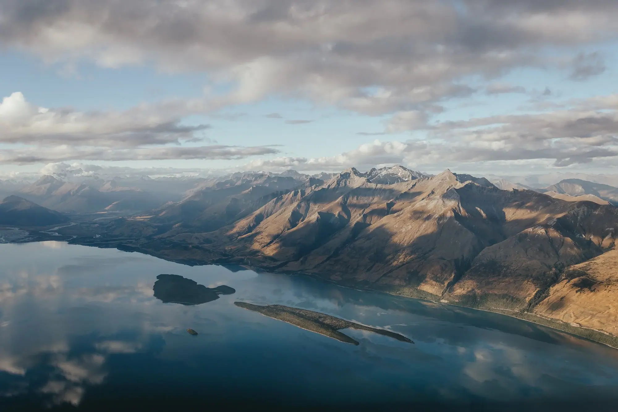 A couple embracing on an alpine ridge above Queenstown after their helicopter elopement
