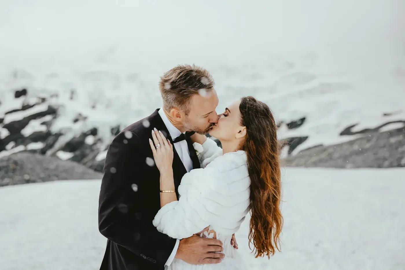 Couple kissing in falling snow on a mountain top near Queenstown