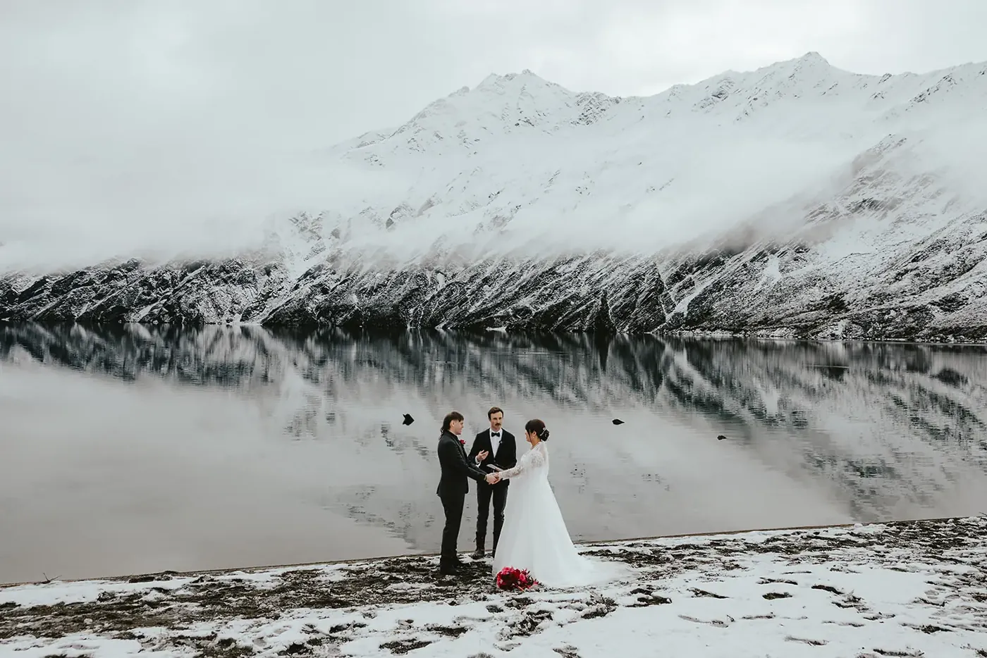 Spring wedding ceremony with a celebrant on the snowy shore of Lake Lochnagar