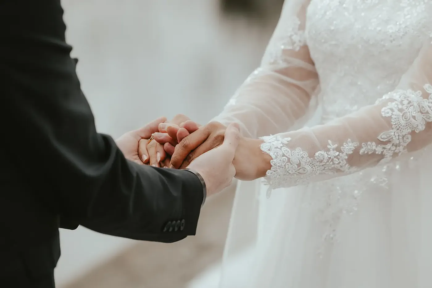 Bride and groom holding hands at their Lake Lochnagar wedding, lace sleeves in winter light