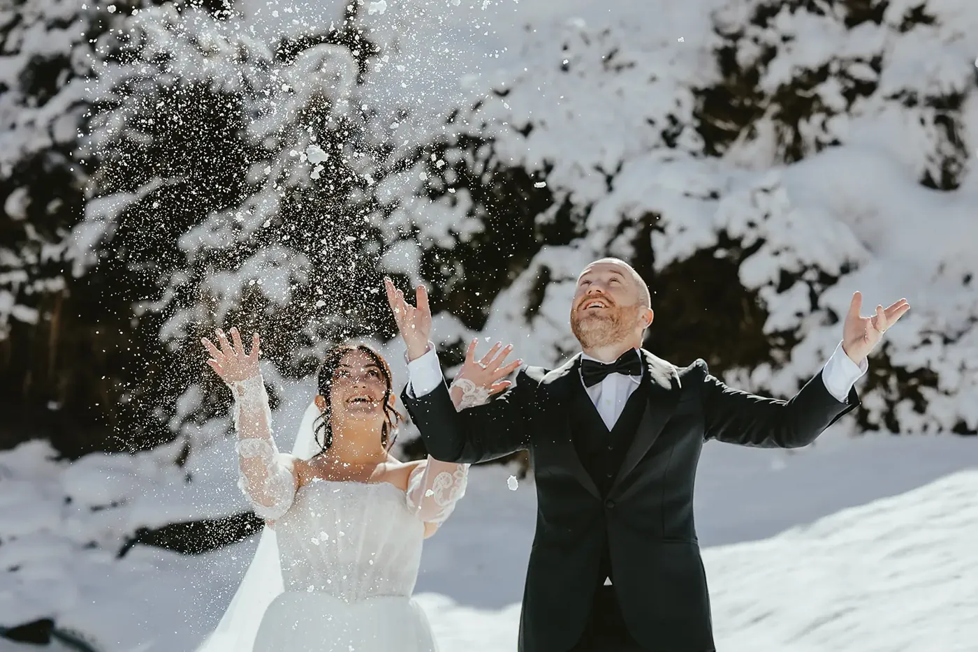 Bride and groom throwing snow into the air at their Lake Lochnagar winter wedding