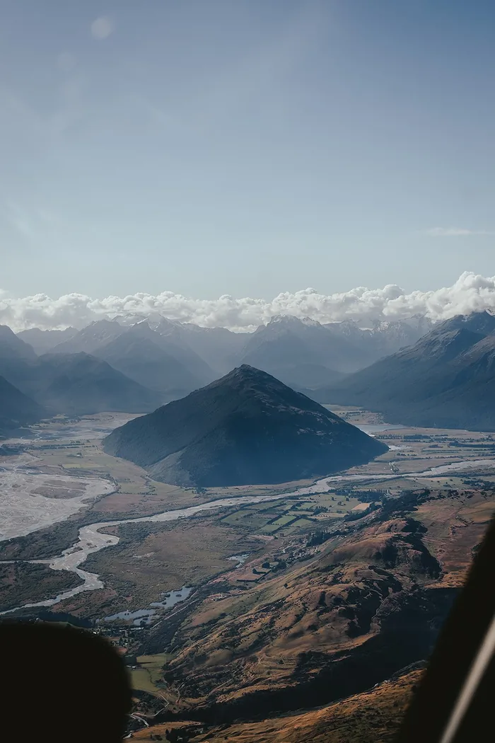 View of a mountain valley and braided river seen from a helicopter window.