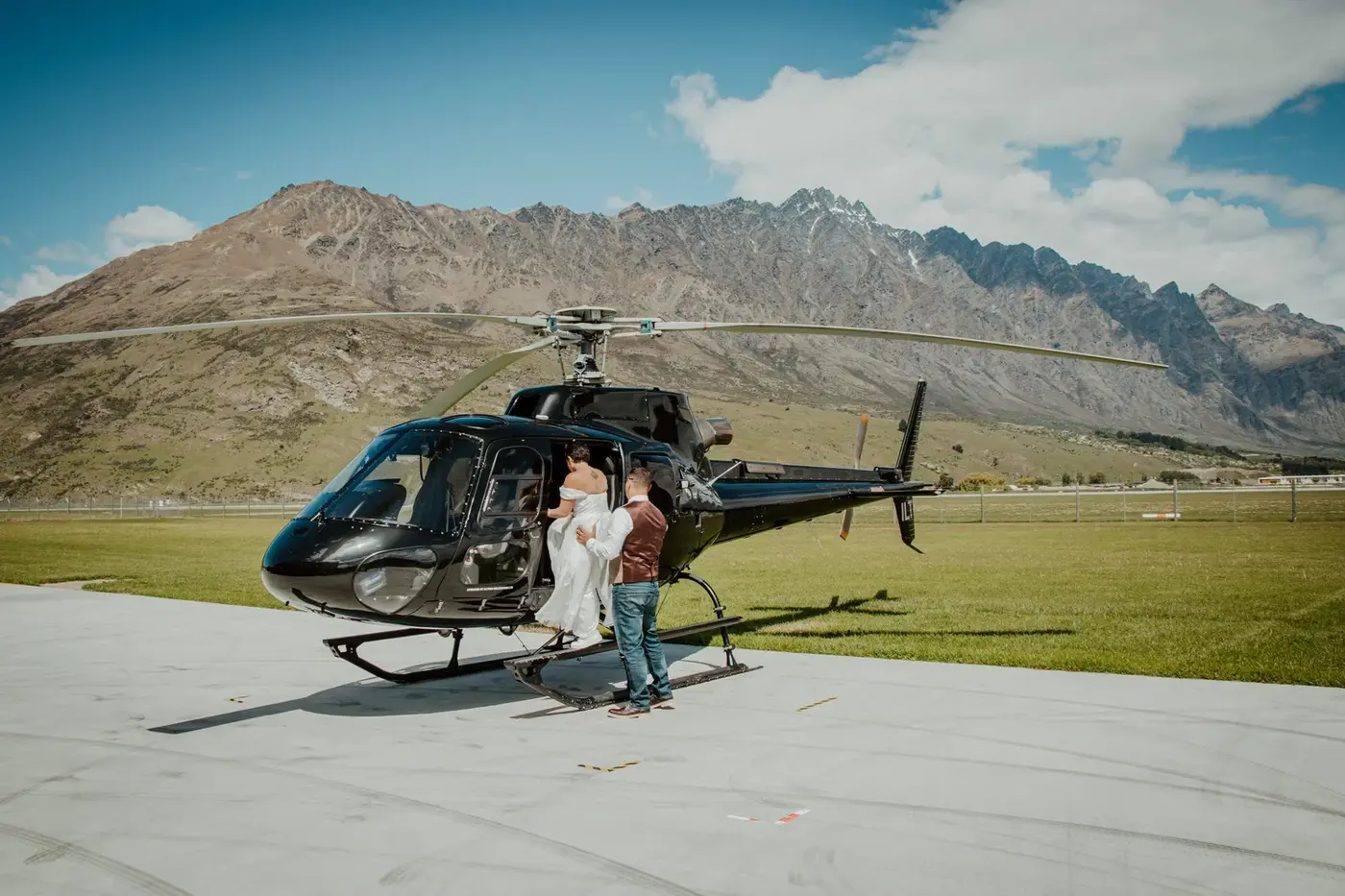 A couple exchanging vows with a celebrant on a mountain top above Queenstown.